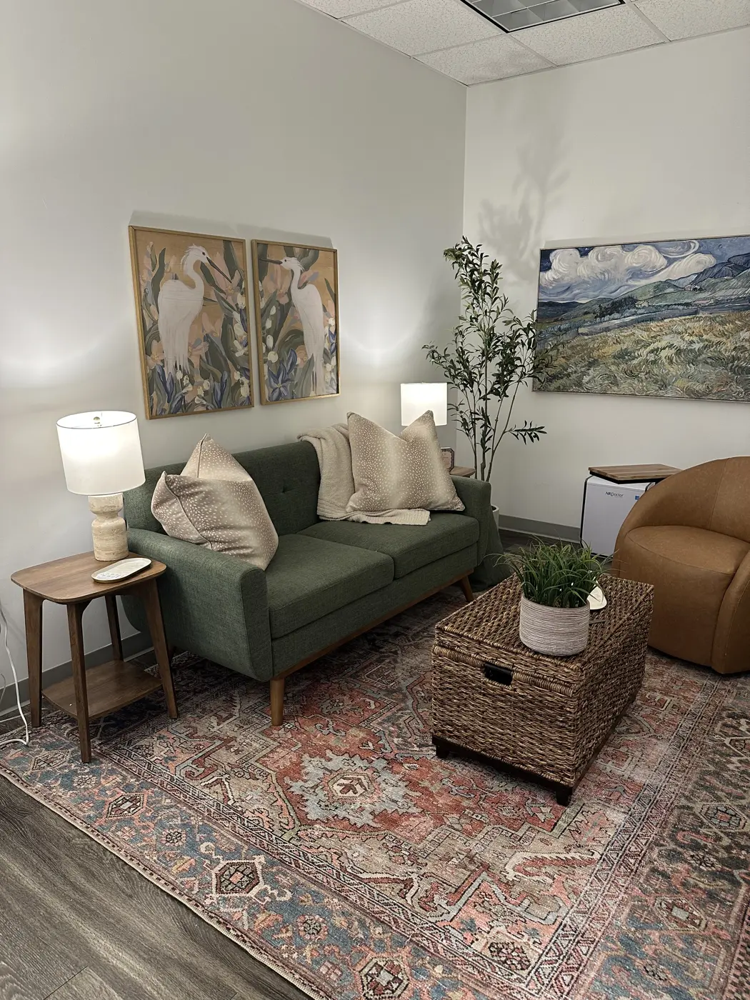 Patti's office sitting room with a green sofa, framed bird prints, and a warm patterned rug.